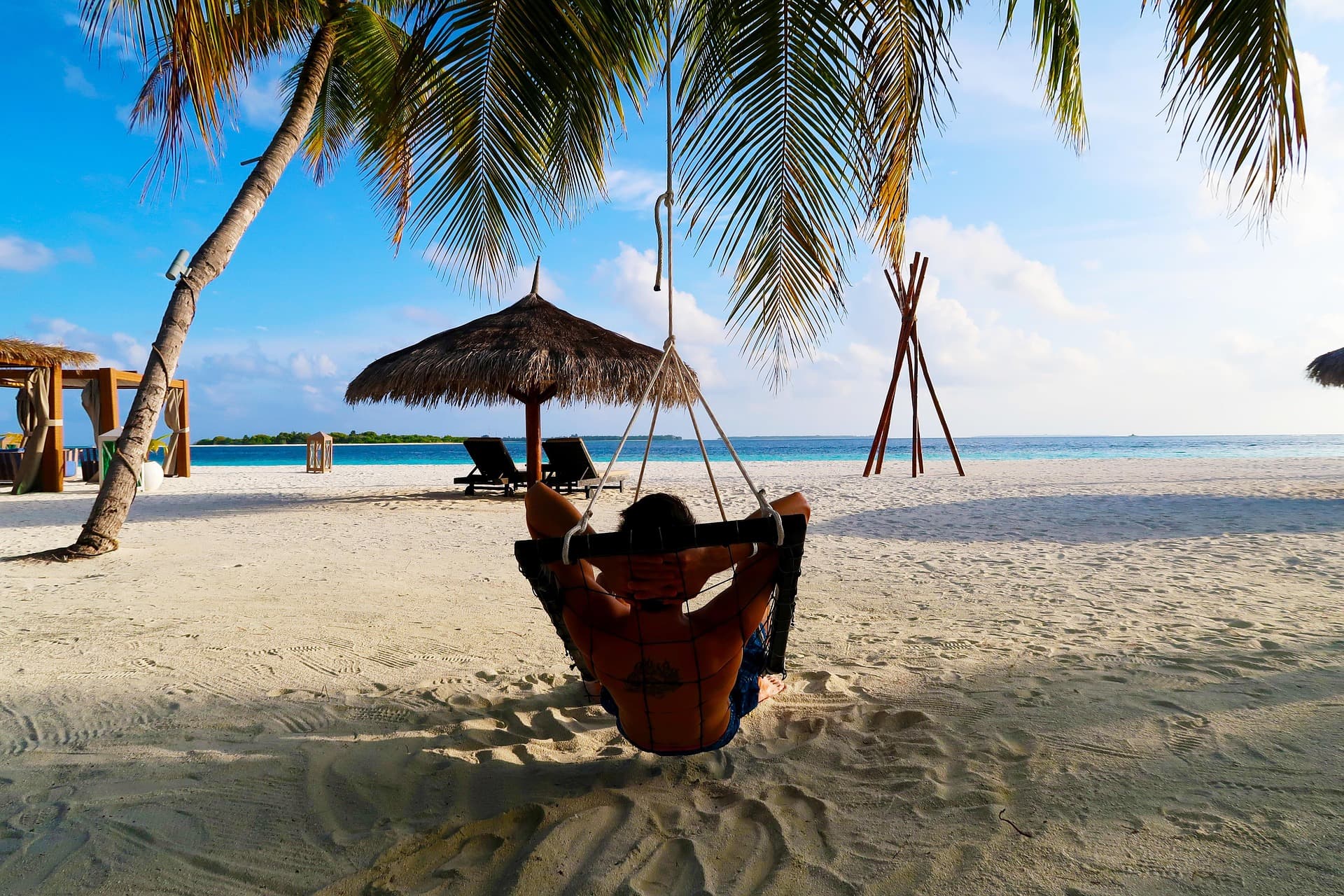 Relaxing in a hammock on a Maldives beach under a palm tree